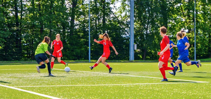 Sports Photography: Freeze the Moment, Capture the Thrill 10 Female football player kicking ball while opponent goalkeeper trying to defend during match.